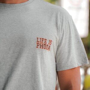 Close-up of a man in a gray crew neck t-shirt with text detail outdoors.