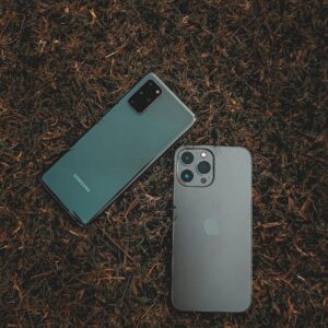 Top view of Samsung and iPhone placed on a grassy surface, showcasing modern smartphone design.