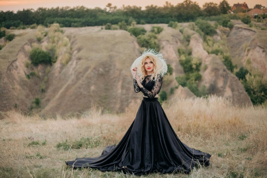 Striking fashion portrait of a woman in a flowing black dress against a rugged desert backdrop.