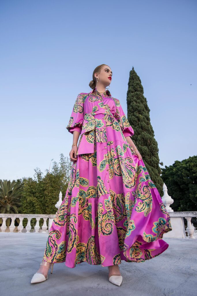 Woman posing outdoors in a stylish purple dress against a clear sky, embodying elegance and sophistication.